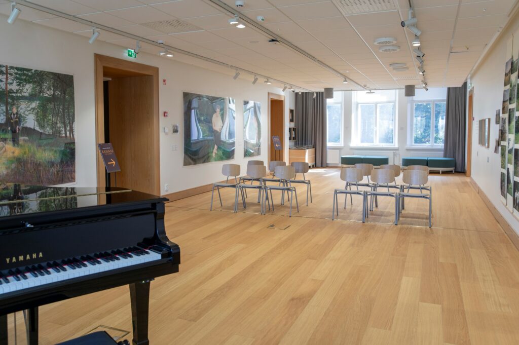 Sali, jossa etualalla flyygeli. Seinillä taidetta.