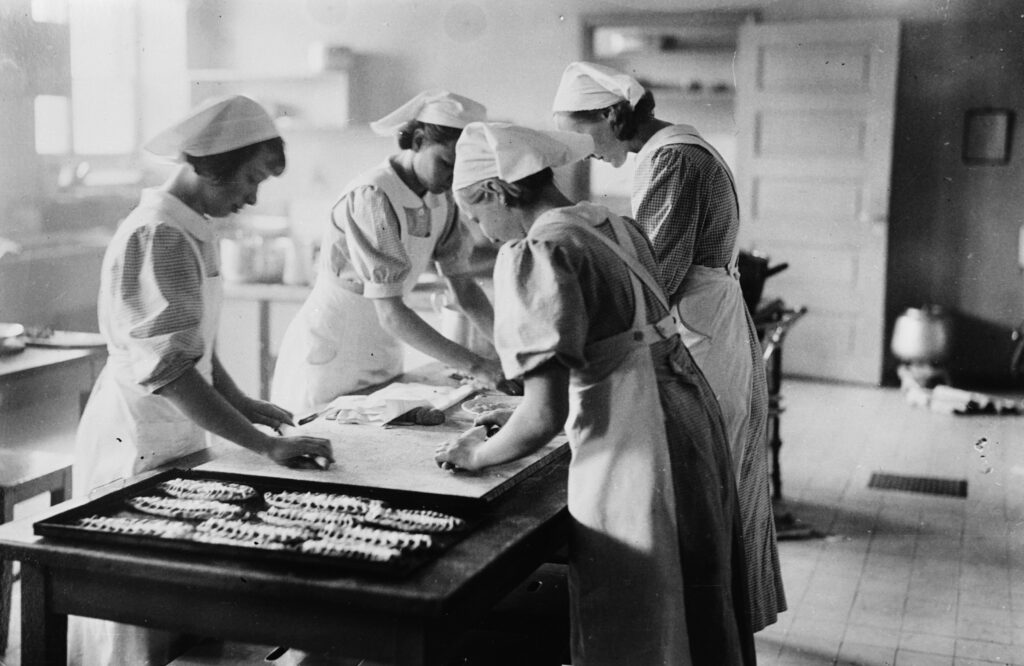 Neljä naista pöydän äärellä leipovat karjalanpiirakoita